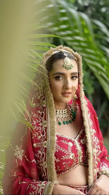 The bride half hidden behind a green leaf, looking into the lens