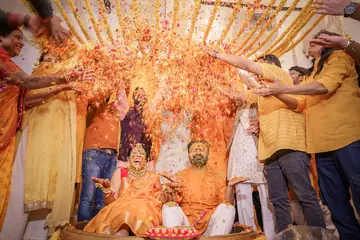Family showers marigold petals over the couple at their haldi