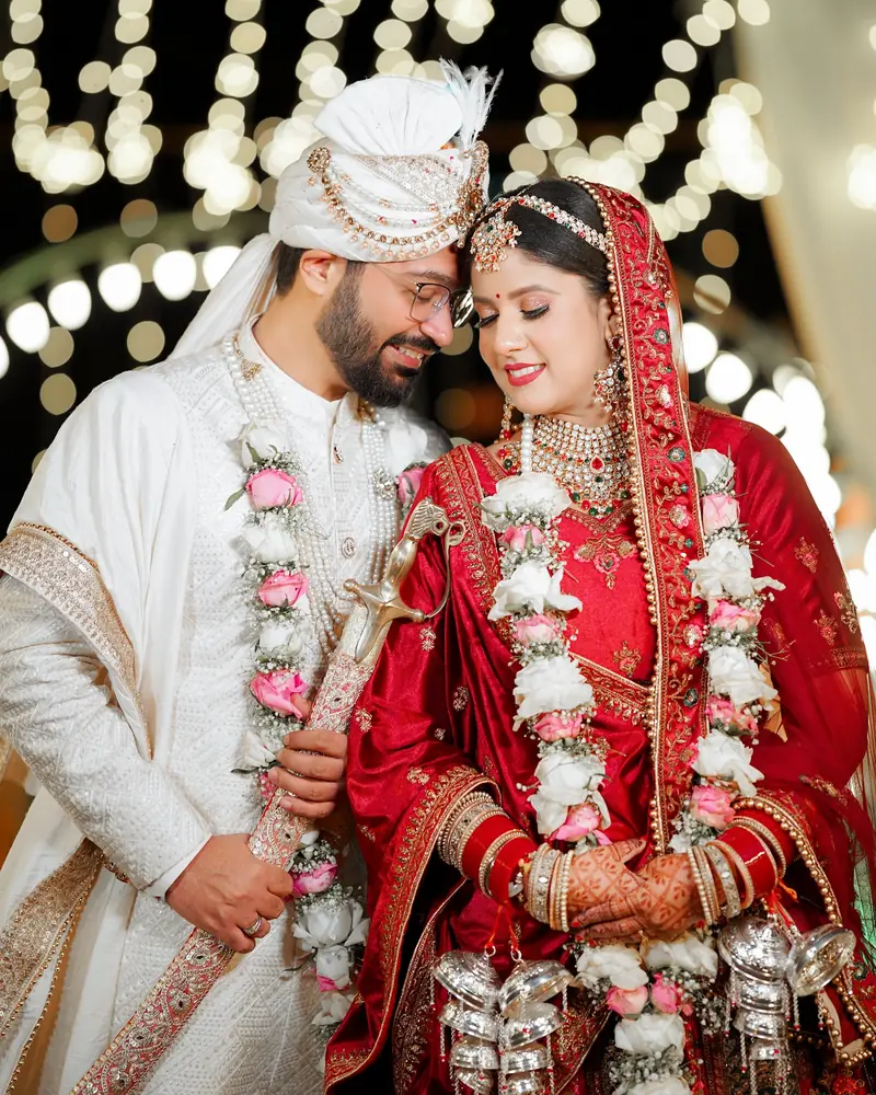 Pransh and Gunjan touch foreheads in their varmalas, fairy lights blurred behind them