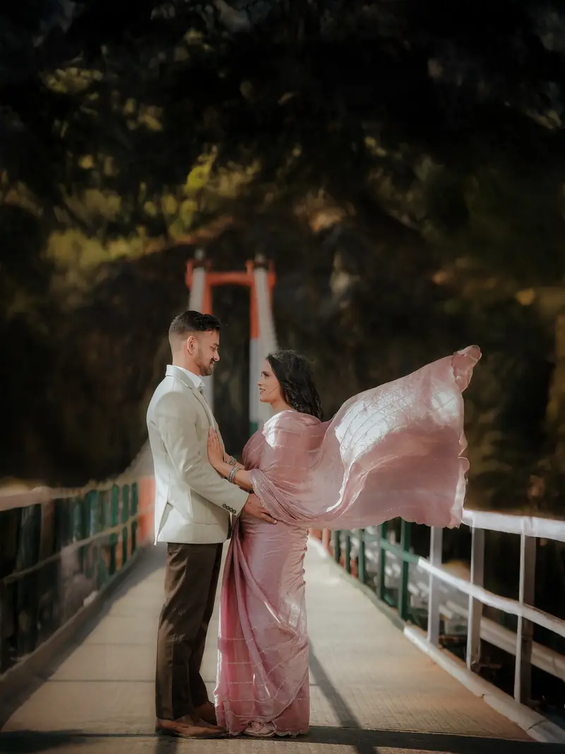 A couple on a suspension bridge, her blush saree caught by the wind