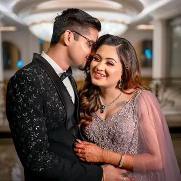 Bhavya laughs as Vaibhav leans in close, a chandelier glowing behind them
