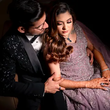 Vaibhav holds Bhavya close in her lilac gown against a dark background